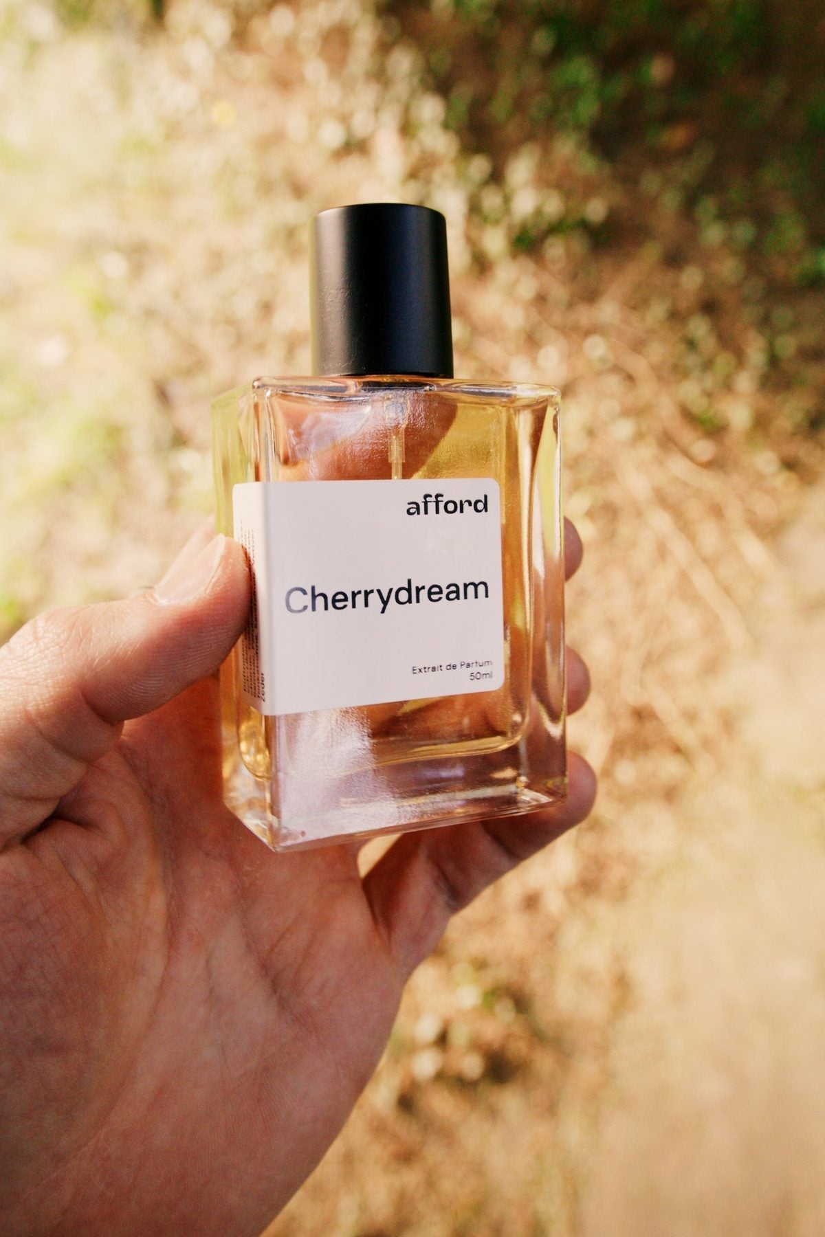 Hand hält den Afford-Flakon Cherrydream im Herbstlicht